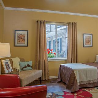 Cozy bedroom with a single bed, armchair, and decorative artwork.