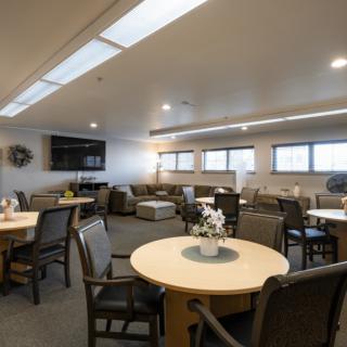 A modern lounge area with tables, chairs, and a television.
