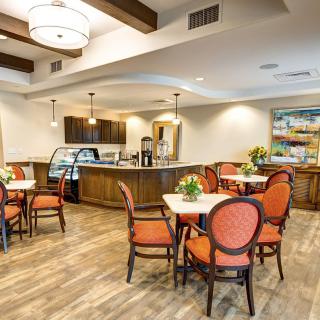 A cozy cafe interior with tables and chairs, featuring warm lighting and a coffee bar.