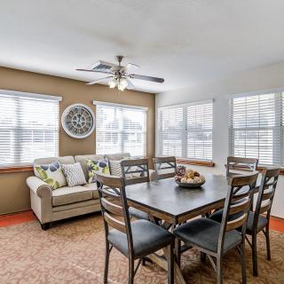A cozy dining area with a table set, surrounded by windows and a sofa.