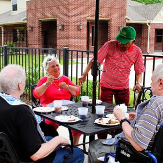 Seniors enjoying a meal together outdoors, engaging in lively conversation.