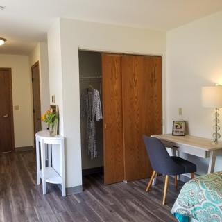 A cozy bedroom with a desk and chair, wooden closet doors, and modern decor.