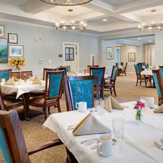 An elegantly furnished dining room with neatly arranged tables and decorative lighting.