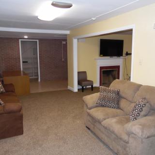 A cozy living room featuring a sofa, television, and fireplace.