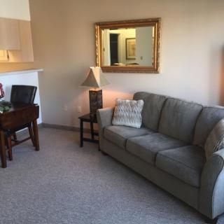 A cozy living room with a sofa, lamp, mirror, and desk.