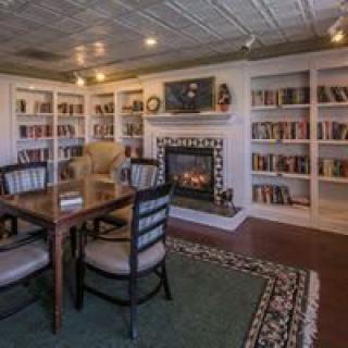 A cozy library room with bookshelves, a fireplace, and a seating area.