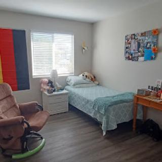 A cozy bedroom setup featuring a bed, chair, and personal decor.