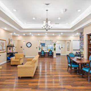 A spacious and elegantly designed lounge area with comfortable seating, hardwood floors, and a chandelier.