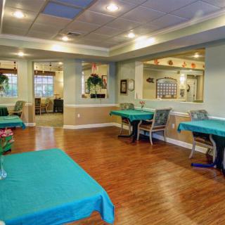 A well-lit dining area with several tables and chairs, featuring a wooden floor and decorative elements.