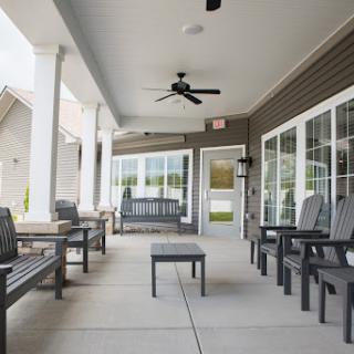 A serene outdoor patio featuring comfortable seating and a ceiling fan, ideal for relaxation.