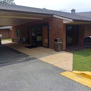 A view of a brick building entrance with a covered area and parking space.