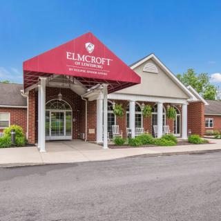Front view of a commercial building with a red awning and well-maintained landscaping.