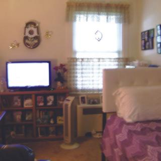 A cozy bedroom with a television, bookshelves, and a neatly made bed.