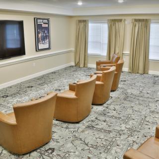 A cozy theater room with a row of comfortable chairs facing a large screen.