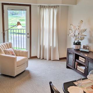 A cozy living room with an armchair, decorative table, and window with curtains.