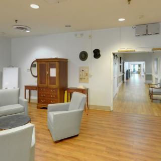 A spacious waiting area with comfortable seating and a wooden floor, leading to a hallway.