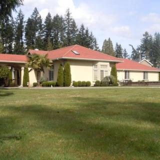 A suburban house with a red roof and expansive lawn surrounded by trees.