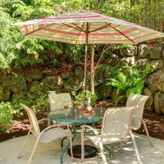 Outdoor patio set with table, chairs, and umbrella in a garden setting.