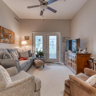 A cozy living room featuring a plush sofa, armchair, TV, and ceiling fan with soft lighting.