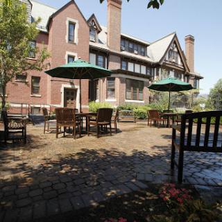 A quaint outdoor patio area featuring tables under umbrellas next to a historic brick building.