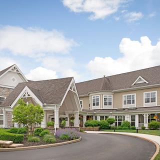 A large residential building with a landscaped driveway under a partly cloudy sky.