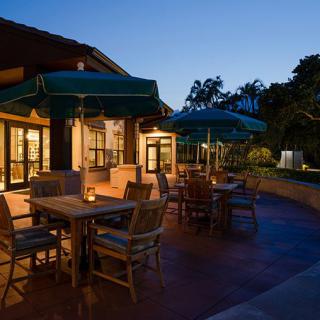 A peaceful outdoor dining area with tables and umbrellas at dusk.