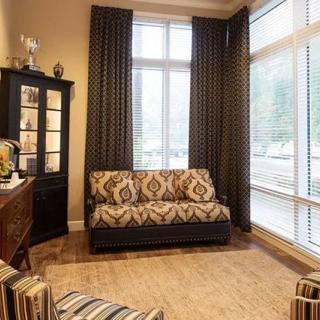 A cozy living room with patterned furniture and floor-to-ceiling windows.
