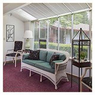 A cozy sunroom with wicker furniture and large windows allowing natural light to fill the space.