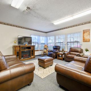 A cozy living room featuring leather sofas and a television, with ample natural light from large windows.