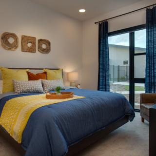 A modern and cozy bedroom with colorful bedding and natural light.