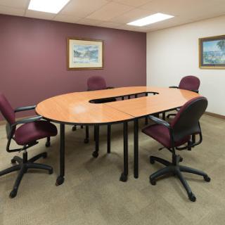 A well-furnished conference room featuring an oval meeting table surrounded by chairs.