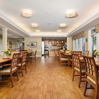 Spacious dining room with wooden flooring and a view into the kitchen area.