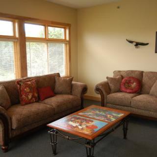 A cozy living room with two sofas and a decorative coffee table near large windows.