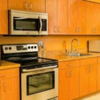 A modern kitchen with wooden cabinets, a stainless steel stove and microwave, and a sink.