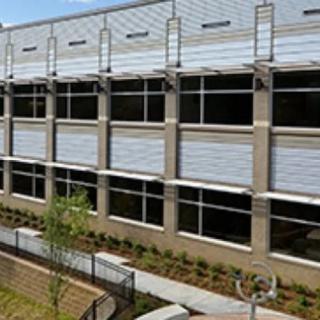 A modern building exterior with multiple windows and a landscaped area.