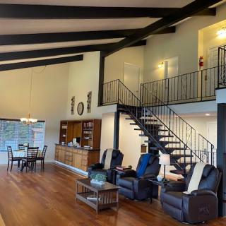 Spacious living room with modern decor, featuring a staircase and dining area.