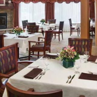 A well-arranged dining room with elegantly set tables and floral centerpieces.