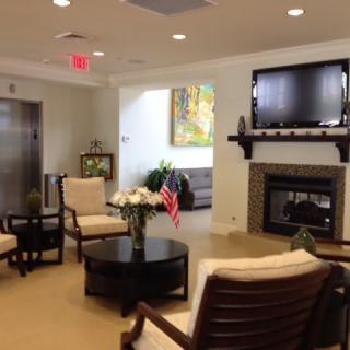 A cozy waiting area with comfortable seating, a television mounted above a fireplace, and tasteful decorations.