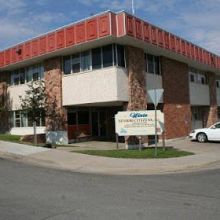A two-story office building with a sign and a parked car in front.