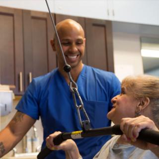 A therapist assisting a patient with physical exercises in a healthcare setting.