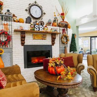 A cozy living room decorated for autumn, featuring a warm fireplace and seasonal elements.
