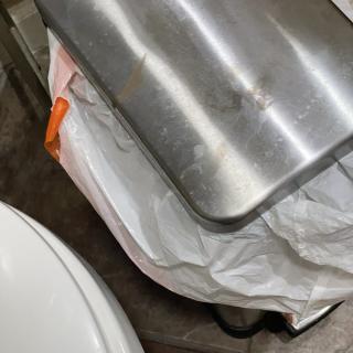 A stainless steel trash can with a white garbage bag inside.