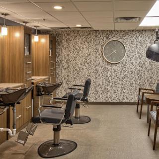 A modern hair salon featuring stylish chairs and elegant wall decor.