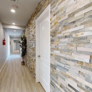 A modern hallway with stone walls, wood flooring, and a white door.