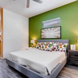 A cozy modern bedroom featuring a vibrant green accent wall, floral patterned pillows, and stylish nightstands.