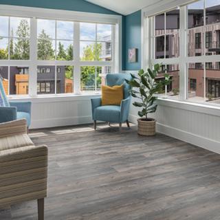 A modern living room with large windows, wood flooring, and a cozy armchair.