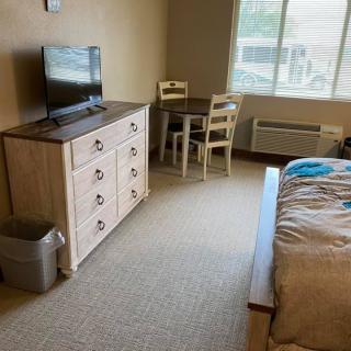 Cozy bedroom with a dresser, TV, and seating area by the window.