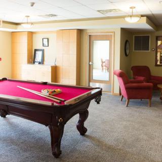A cozy game room featuring a billiard table with a red felt surface and surrounding furniture.