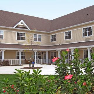A two-story residential building with a landscaped garden in the foreground.