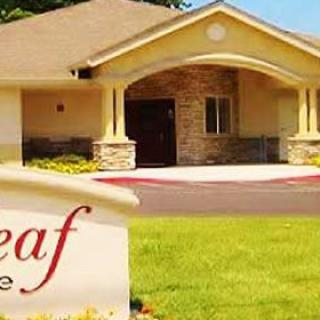 A welcoming entrance to a residential building with a manicured lawn and sign in the foreground.